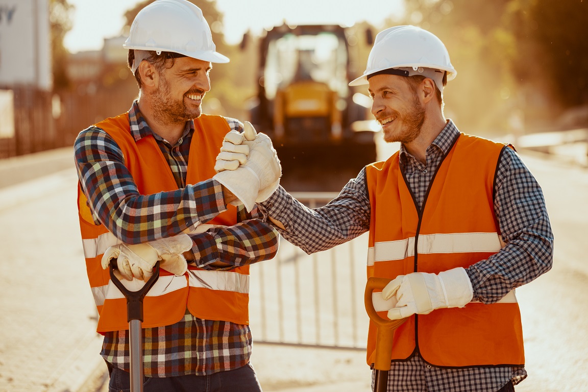 Smiling coworkers in reflective vests and white helmets after ro