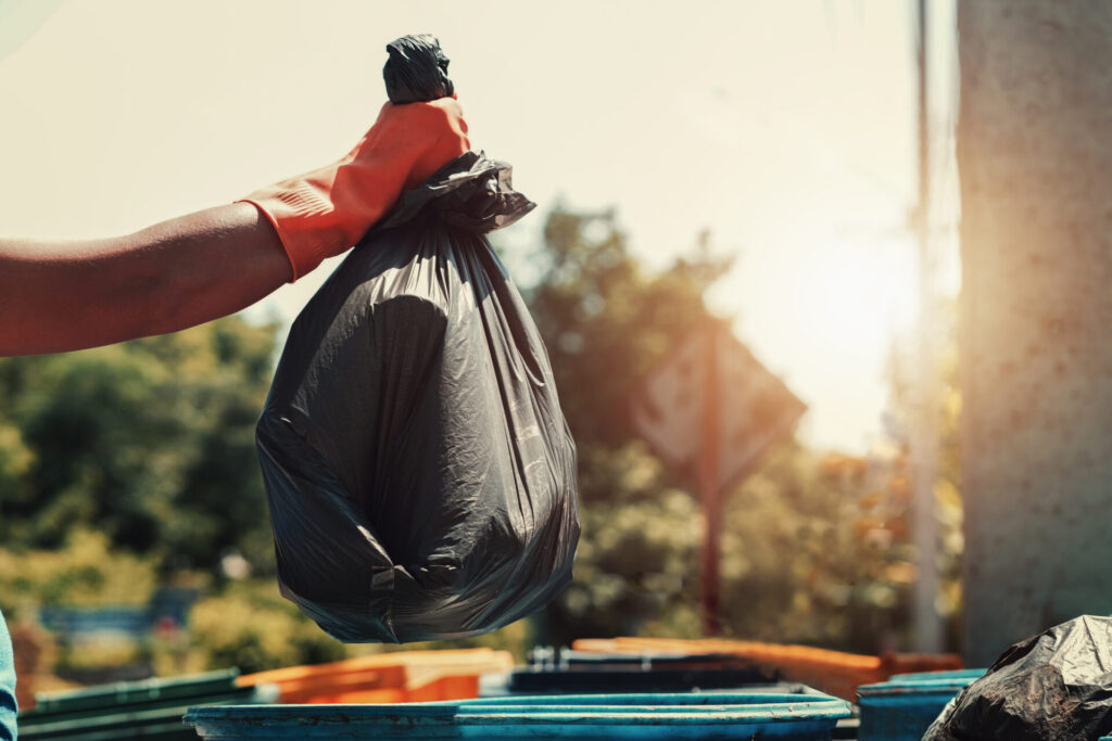hand holding garbage black bag putting in to trash